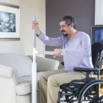 A man moving from a sofa to his wheelchair using an Advantage rail floor-mounted grab bar and support.