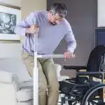 A man moving from a sofa to his wheelchair using an Advantage rail floor-mounted grab bar and support.