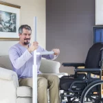 A man moving from a sofa to his wheelchair using an Advantage rail floor-mounted grab bar and support.