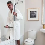 A man is using the Superpole with Superbar to exit the shower.