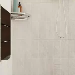 Folded SerenaSeat installed white tile shower wall.