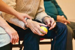 The hand of a care taker holding the wrist of an older adult.